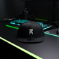 Black Rebellion x New Era snapback hat with white embroidered logo, resting on a gaming desk with RGB keyboard and mouse.