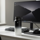 Black and white water bottle on a desk with a computer monitor and keyboard in the background